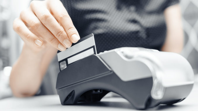 Bank terminal and a woman's hand with a credit or debit card to make payments. Bank terminal and a woman's hand with a credit or debit card to make payments.